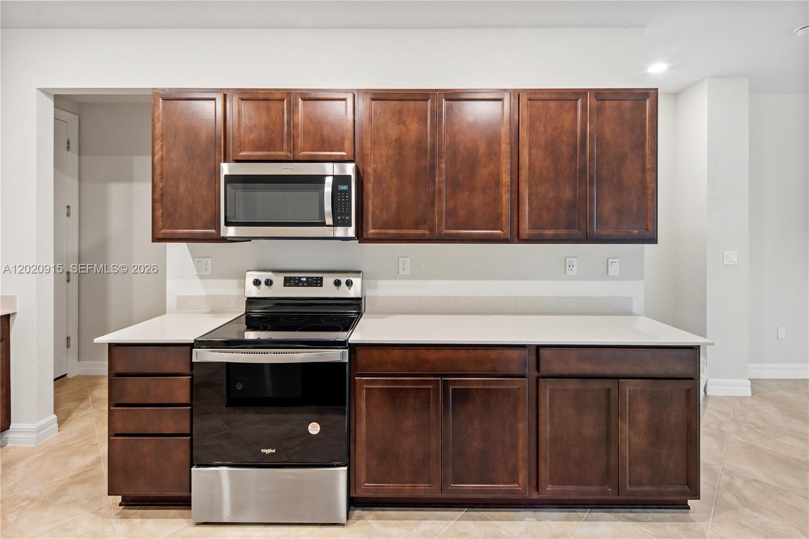 A kitchen features dark wood cabinets, stainless steel appliances, and white countertops — 4488 E Appleton Cir E, Oakland Park FL 33309, OAKLAND PARK, FL