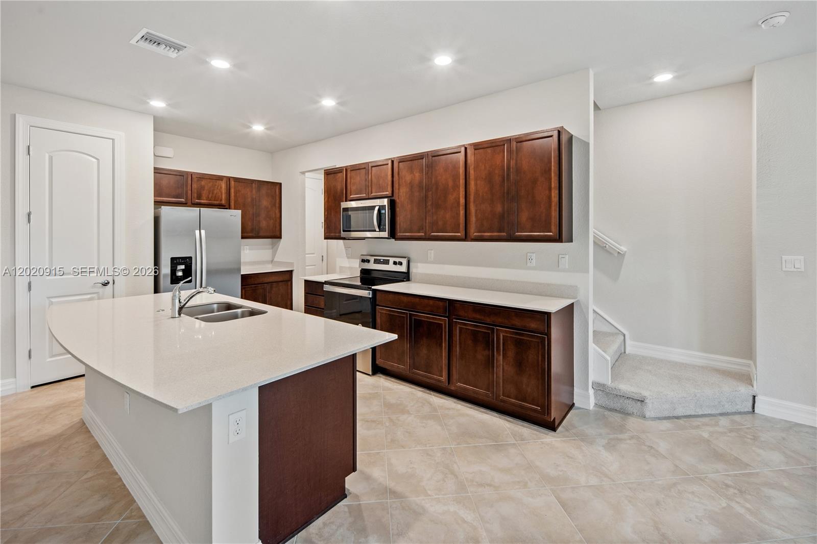 A kitchen features dark wood cabinets, stainless steel appliances, and a large quartz island — 4488 E Appleton Cir E, Oakland Park FL 33309, OAKLAND PARK, FL