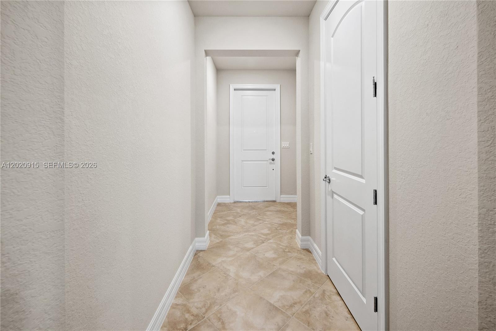 A hallway with beige tile flooring, white walls, and two white interior doors — 4488 E Appleton Cir E, Oakland Park FL 33309, OAKLAND PARK, FL