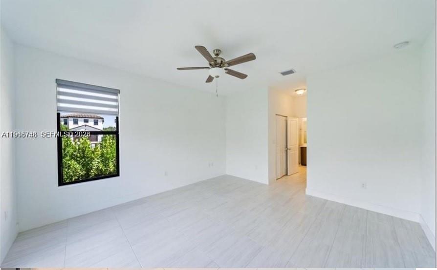 An empty bedroom features white walls, light tile flooring, a ceiling fan, and a window — 5501 Agostino way, Ave Maria FL 34142, AVE MARIA, FL