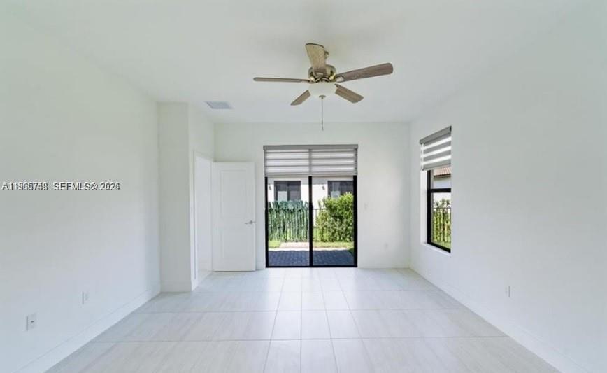 A bright, empty room features white walls, light tile flooring, a ceiling fan, and sliding doors — 5501 Agostino way, Ave Maria FL 34142, AVE MARIA, FL