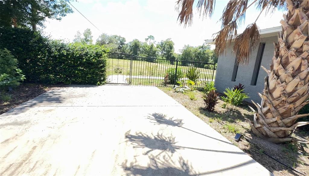 A concrete patio area sits beside a house with a palm tree and metal fencing — 4925 N US HIGHWAY 441, OCALA, FL