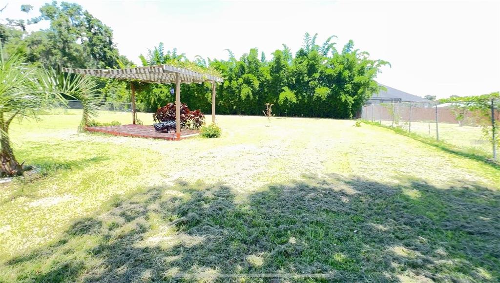 A large backyard features a wooden pergola over a deck and a chain-link fence — 4925 N US HIGHWAY 441, OCALA, FL