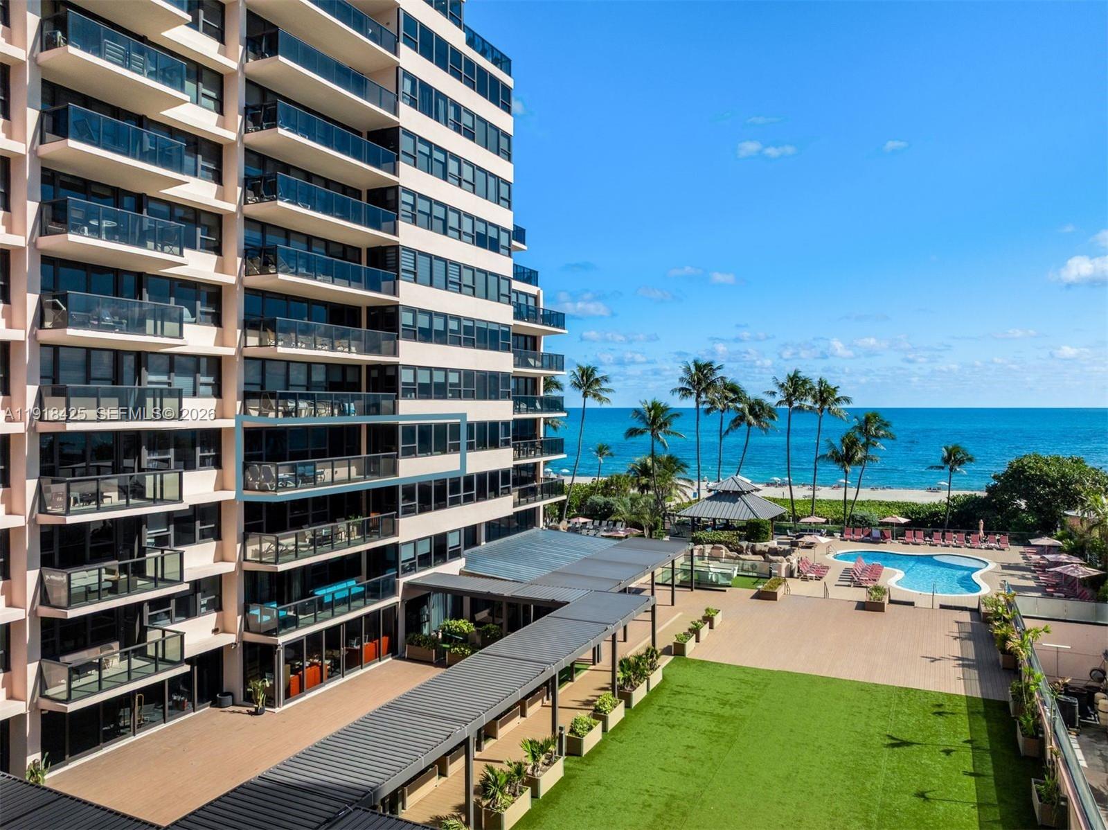 An exterior view of a high-rise building with balconies overlooking a pool and the ocean — 5225 Collins Ave # 603, Miami Beach FL 33140, MIAMI BEACH, FL