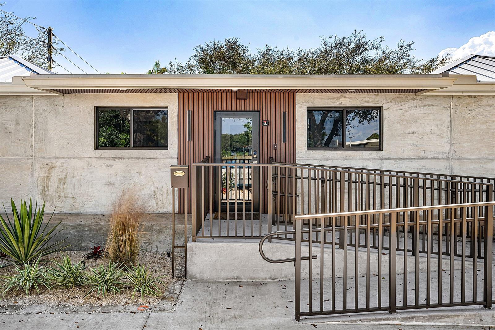 A concrete building exterior features a central wood-slatted entryway with a metal wheelchair ramp — 112 SE 10th Street, Delray Beach FL 33483, DELRAY BEACH, FL