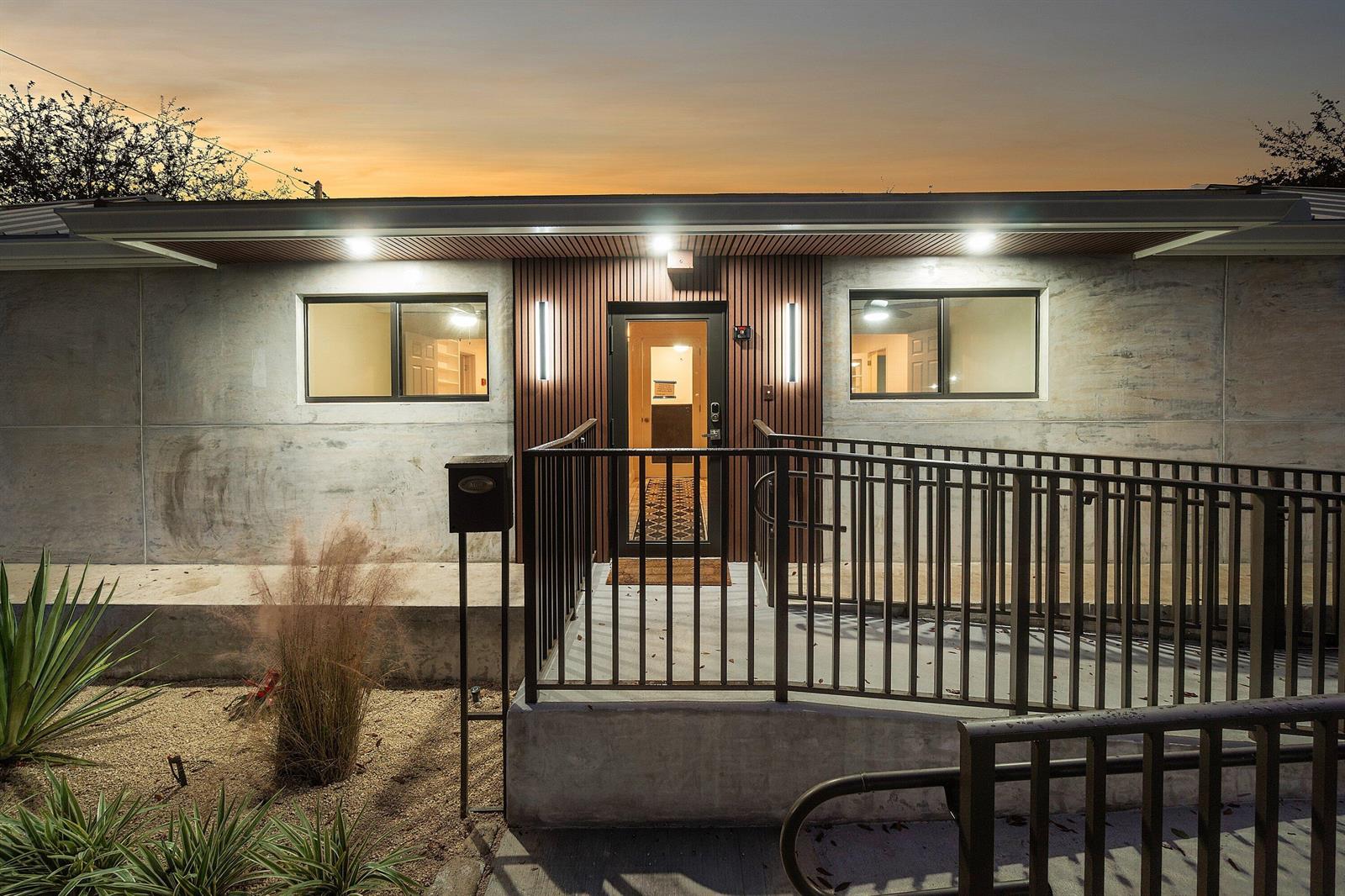 The exterior of a modern house features a concrete facade, wood-slatted entryway, and metal ramp — 112 SE 10th Street, Delray Beach FL 33483, DELRAY BEACH, FL