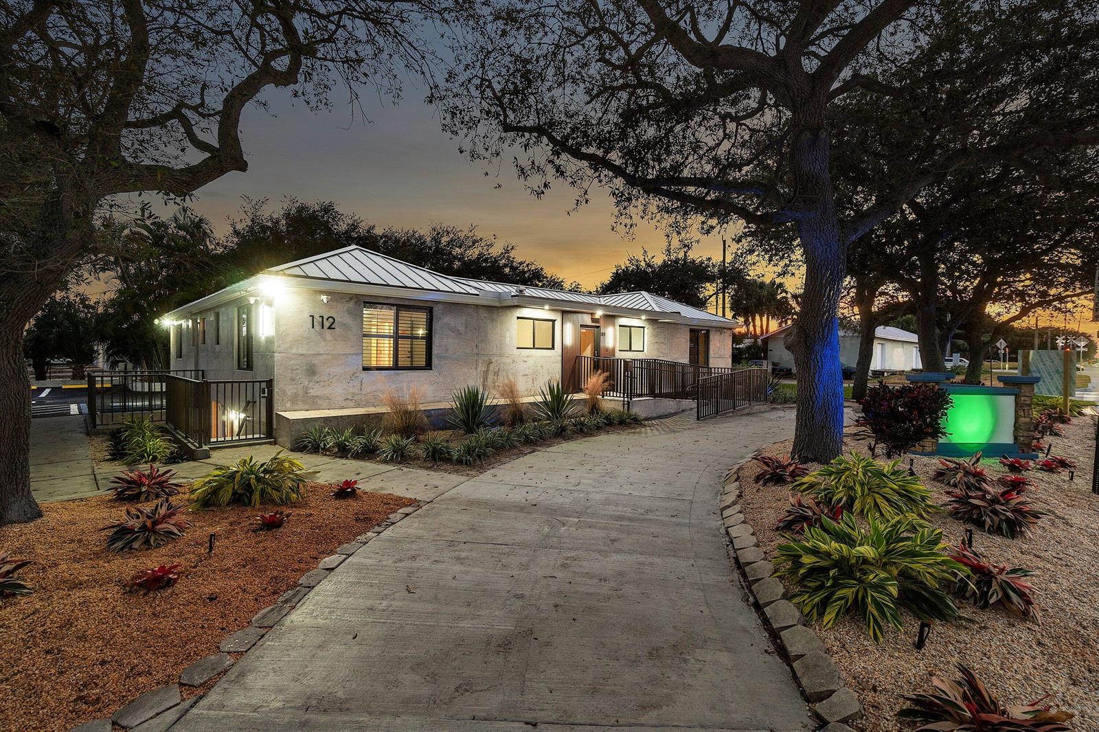 A single-story building with a metal roof and concrete exterior features a curved concrete walkway — 112 SE 10th Street, Delray Beach FL 33483, DELRAY BEACH, FL