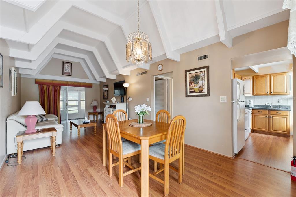 A dining area and living room with vaulted ceilings, wood flooring, and an adjacent kitchen — 3821 CLUB CIRCLE, LAKE WALES, FL