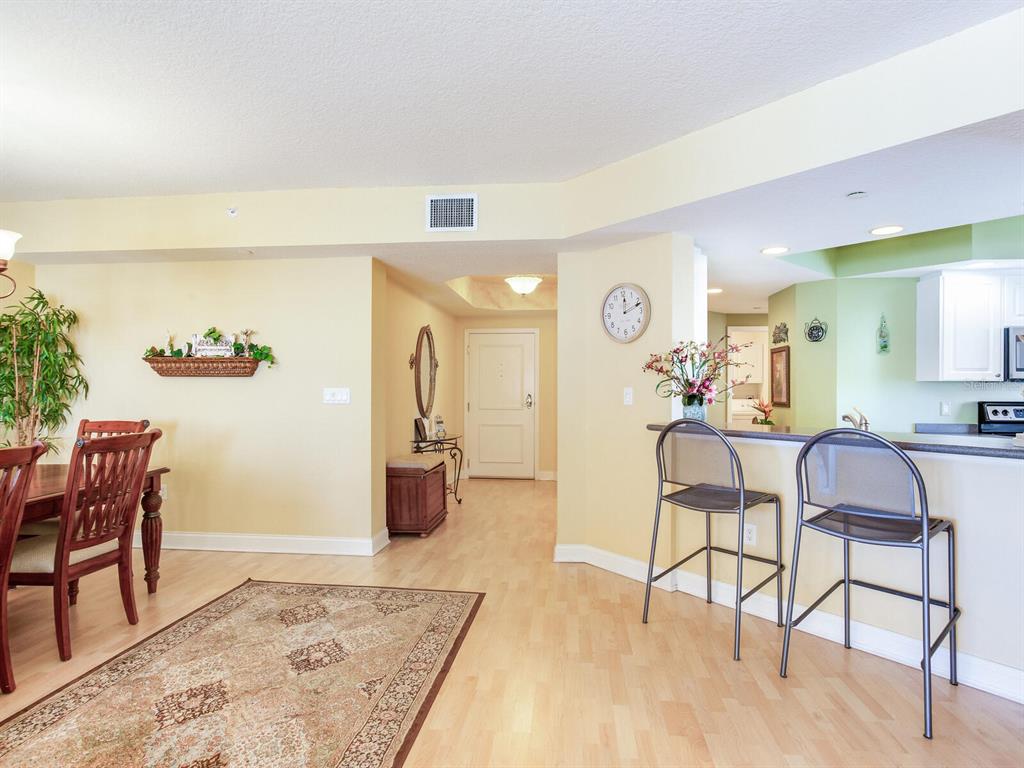 A dining area and kitchen breakfast bar with light wood flooring and yellow walls — 11 SAN MARCO STREET UNIT 807, CLEARWATER BEACH, FL