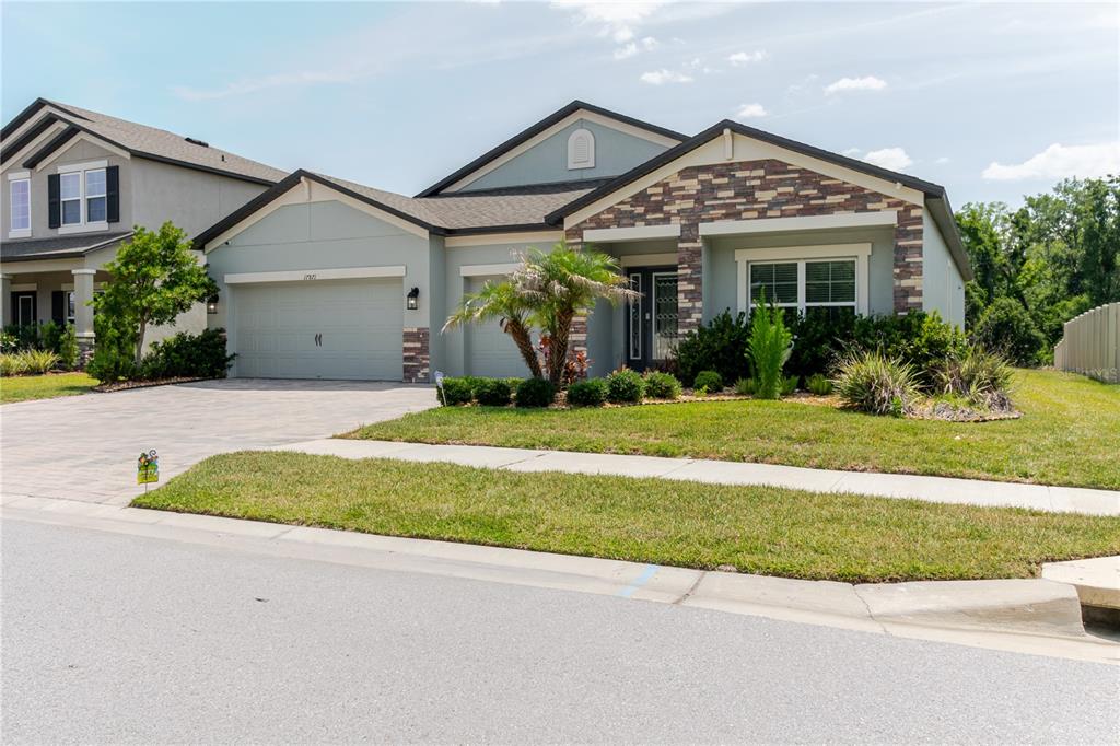 A single-story suburban house with a stone-accented facade, a two-car garage, and a landscaped lawn — 17871 CORTES CREEK BOULEVARD, SPRING HILL, FL