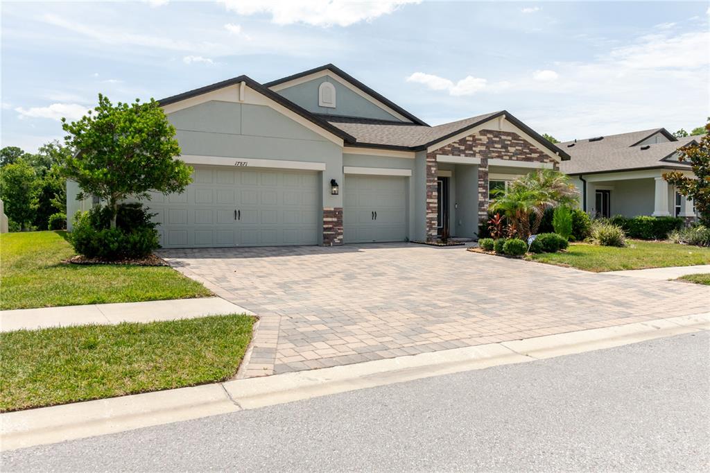 A single-story house with a stone facade, a paved driveway, and a three-car garage — 17871 CORTES CREEK BOULEVARD, SPRING HILL, FL