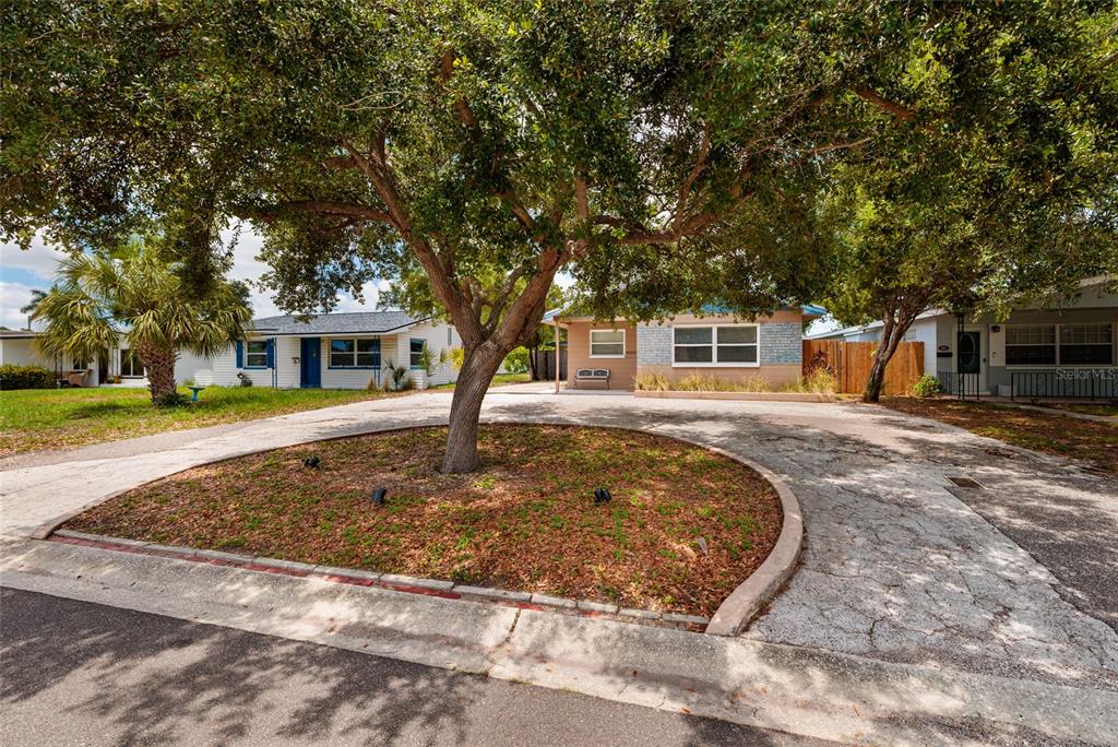 A circular driveway with a central tree leads to a single-story house with a yard — 511 74TH AVENUE N, ST PETERSBURG, FL
