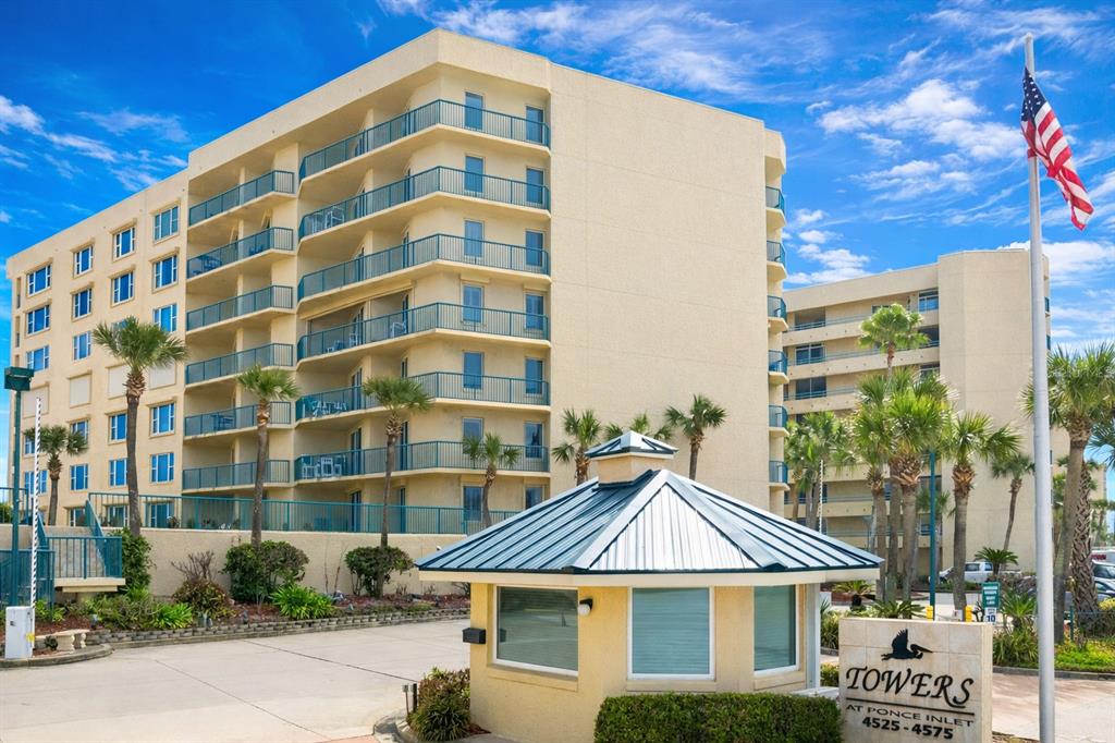 The exterior of a multi-story apartment building features balconies and a gated entrance kiosk — 4555 S ATLANTIC AVENUE UNIT 4506, PONCE INLET, FL