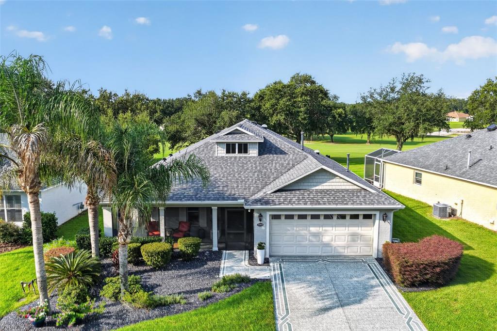 A single-story house with a gray shingled roof, a two-car garage, and a palm tree — 26860 WHITE PLAINS WAY, LEESBURG, FL