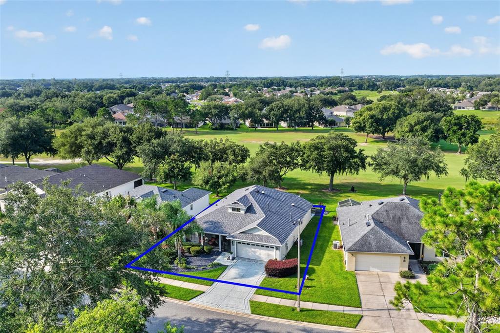 A wide, grassy golf course fairway is framed by large, moss-draped oak trees — 26860 WHITE PLAINS WAY, LEESBURG, FL