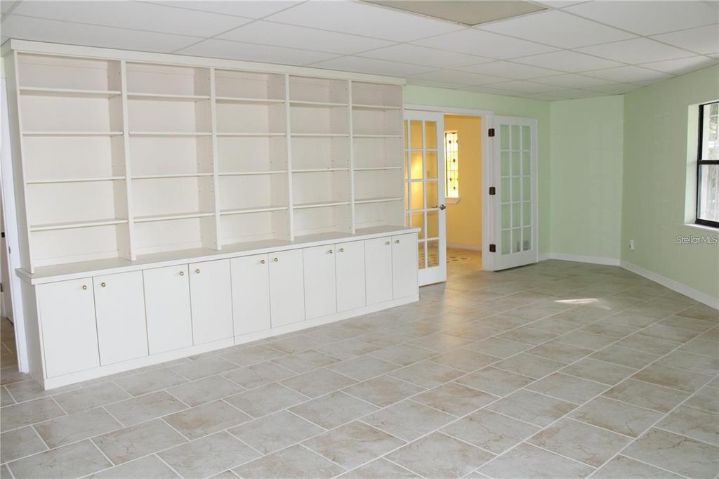 A room with light green walls, tile flooring, a large white bookshelf, and French doors — 5828 OAKHURST DRIVE, SEMINOLE, FL