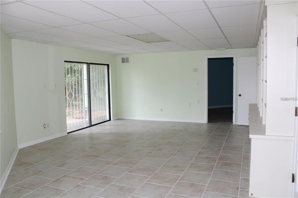 A room with light green walls, tiled flooring, a drop ceiling, and sliding glass doors — 5828 OAKHURST DRIVE, SEMINOLE, FL