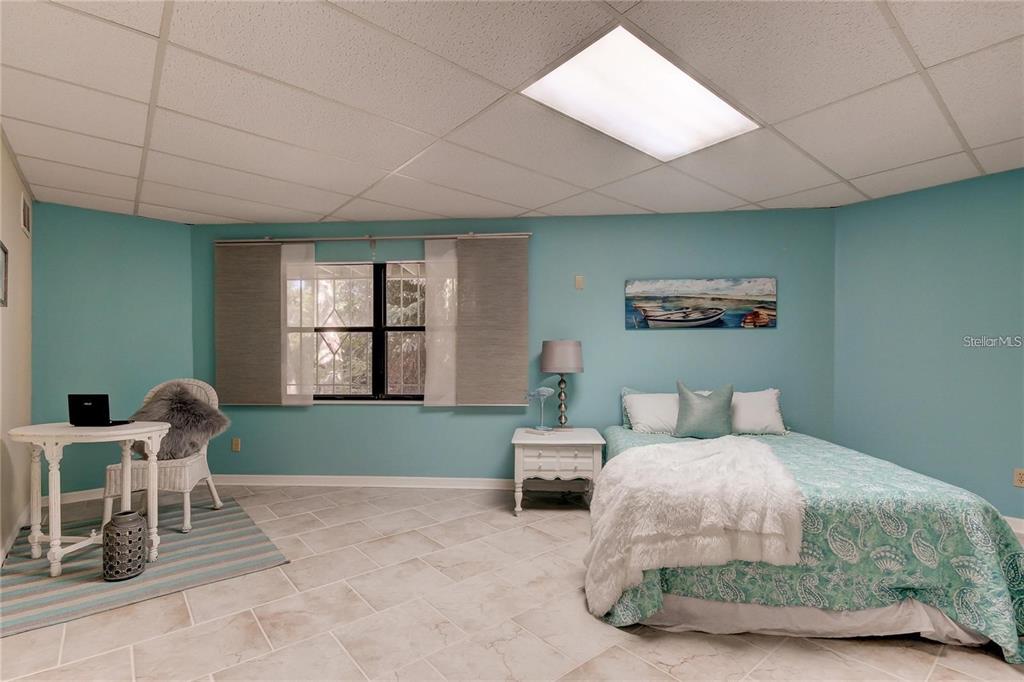 A bedroom with light blue walls, tile flooring, a bed, and a small desk area — 5828 OAKHURST DRIVE, SEMINOLE, FL