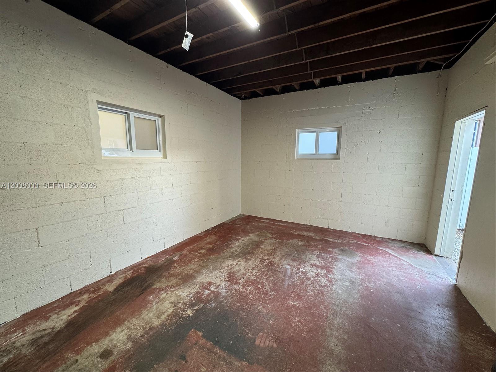 An unfinished room features painted concrete block walls, a red concrete floor, and exposed ceiling joists — 4 NE 47th St, Miami FL 33137, MIAMI, FL