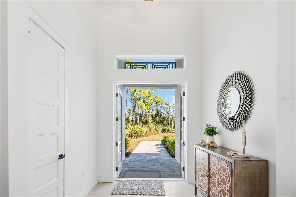 A bright entryway features white walls, a high ceiling, and an open door to outdoors — 143 CREEK DRIVE SE, PORT CHARLOTTE, FL