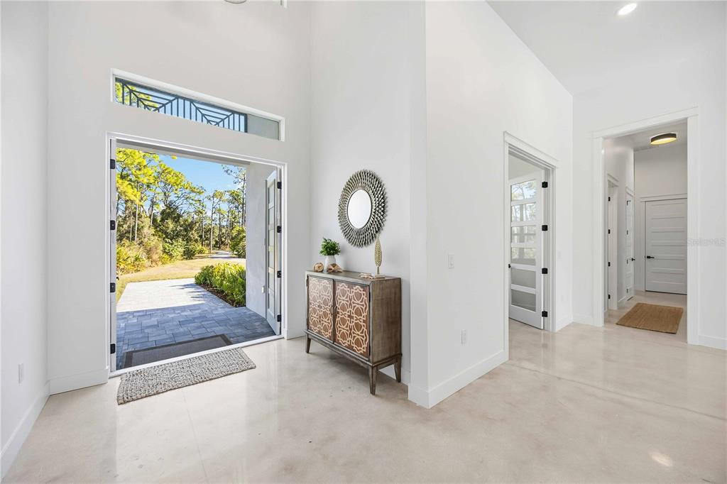 A bright entryway features polished concrete floors, a tall ceiling, and an open front door — 143 CREEK DRIVE SE, PORT CHARLOTTE, FL