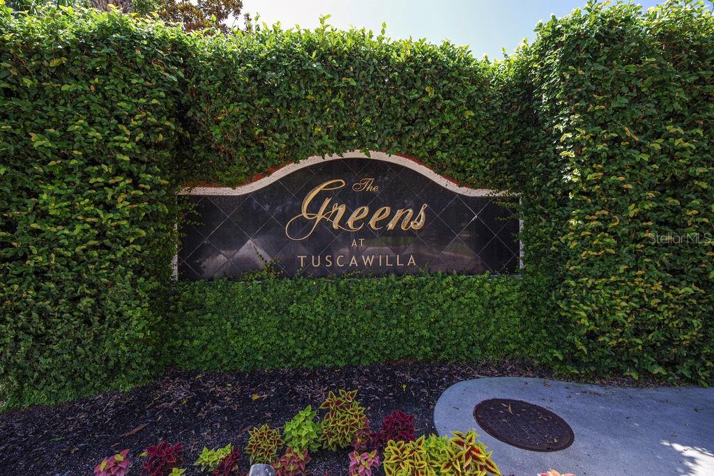 A sign for The Greens at Tuscawilla is set against a dense green hedge — 1541 CORKERY COURT UNIT 1541, WINTER SPRINGS, FL