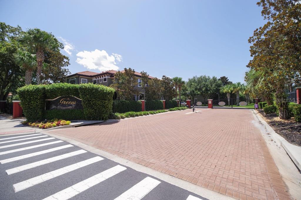A gated entrance with a brick driveway and a sign for The Greens at Town Villa — 1541 CORKERY COURT UNIT 1541, WINTER SPRINGS, FL
