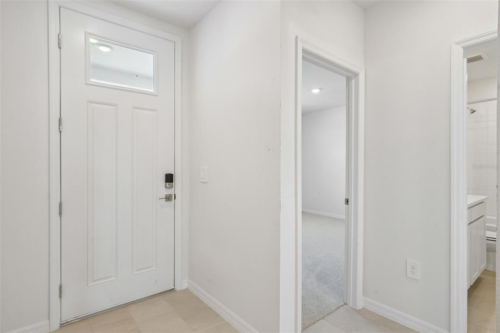 An entryway with a white front door, a doorway to a bedroom, and a bathroom entrance — 13704 UMBER FOREST STREET, HUDSON, FL