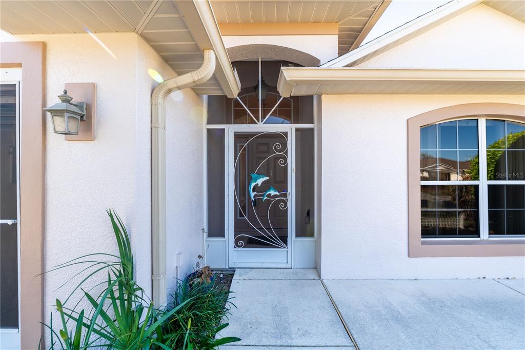 The exterior entrance features a white screen door with dolphin accents and a large window — 4486 N LAKE VISTA TRAIL, HERNANDO, FL
