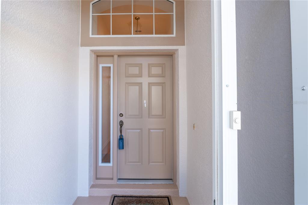 A tan front door with a side window and arched transom sits under a porch — 4486 N LAKE VISTA TRAIL, HERNANDO, FL