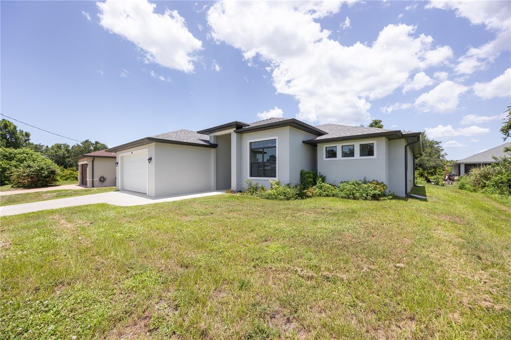 A single-story house with a white garage, gray stucco exterior, and a grassy front yard — 2535 TRICO ROAD, NORTH PORT, FL