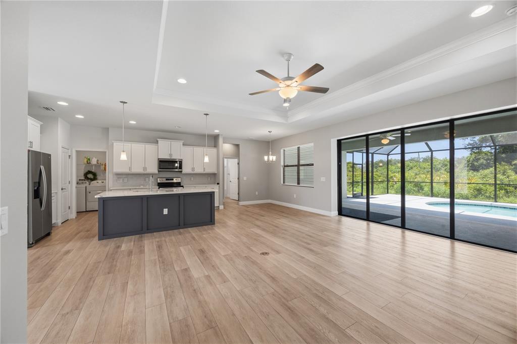 An open-concept kitchen and living area with light wood floors and sliding glass patio doors — 2535 TRICO ROAD, NORTH PORT, FL