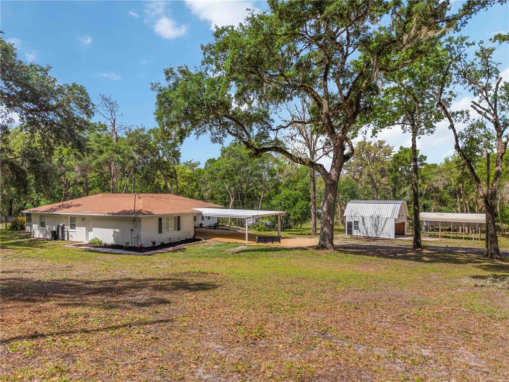 A single-story house with a carport and a detached shed sits on a grassy lot — 2293 SPRING LAKE HIGHWAY, BROOKSVILLE, FL
