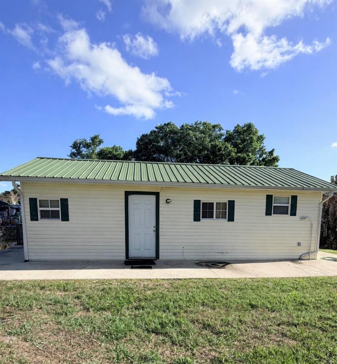 A single-story house with light siding, a green metal roof, and dark green shutters — 4046 SE 26th Street, Okeechobee FL 34974, OKEECHOBEE, FL