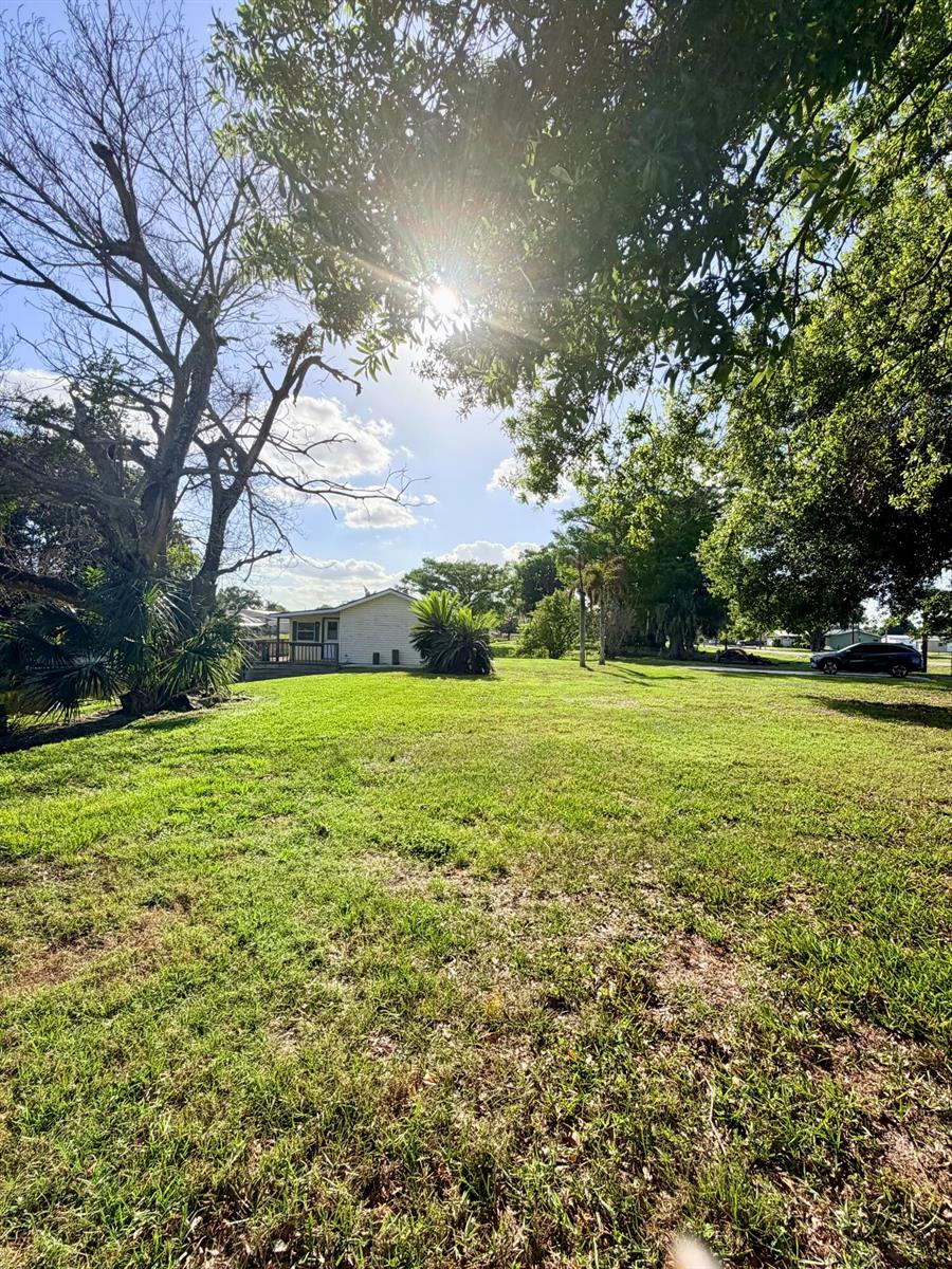 A grassy yard with a house in the distance under a bright, sunlit sky — 4046 SE 26th Street, Okeechobee FL 34974, OKEECHOBEE, FL