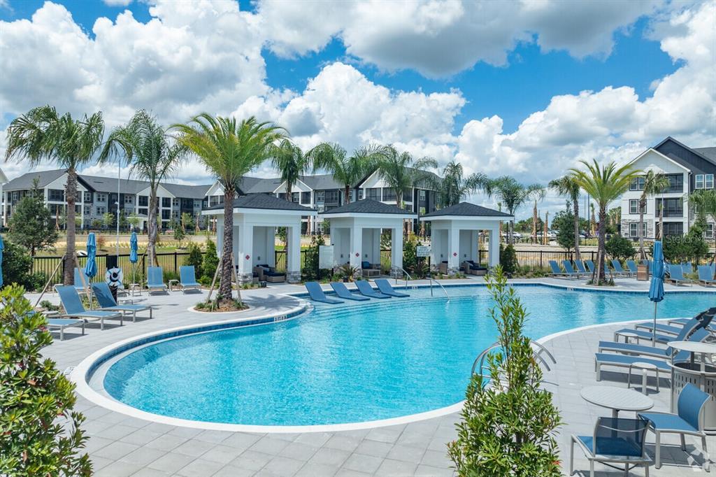 A swimming pool with lounge chairs and cabanas sits in front of multi-story apartment buildings — 3020 BASE BOULEVARD UNIT B2, DAVENPORT, FL