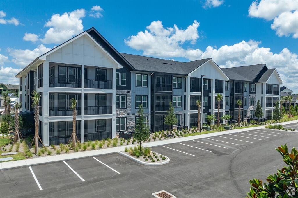 A three-story apartment building with a parking lot in the foreground under a blue sky — 3020 BASE BOULEVARD UNIT B2, DAVENPORT, FL