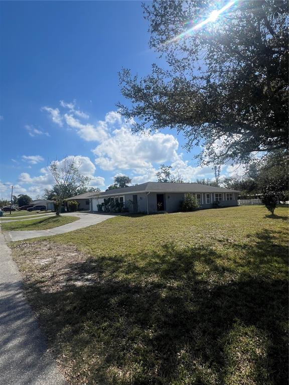 A single-story gray house with a concrete driveway sits on a large, grassy lot — 22065 MALONE AVENUE, PORT CHARLOTTE, FL