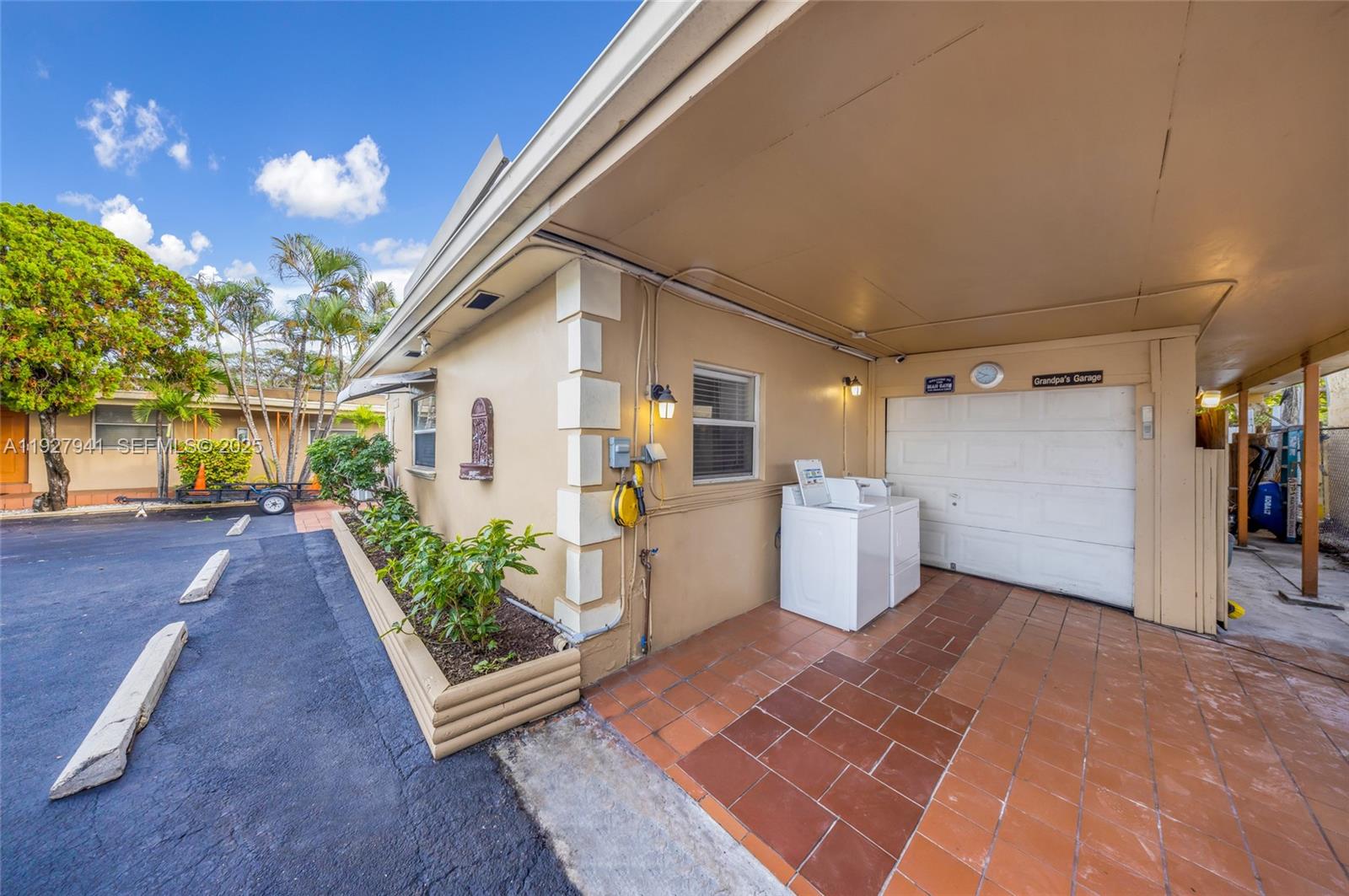 A tan building exterior features a covered carport, a white garage door, and a laundry unit — 6124 Pembroke Rd # 8, Miramar FL 33023, MIRAMAR, FL