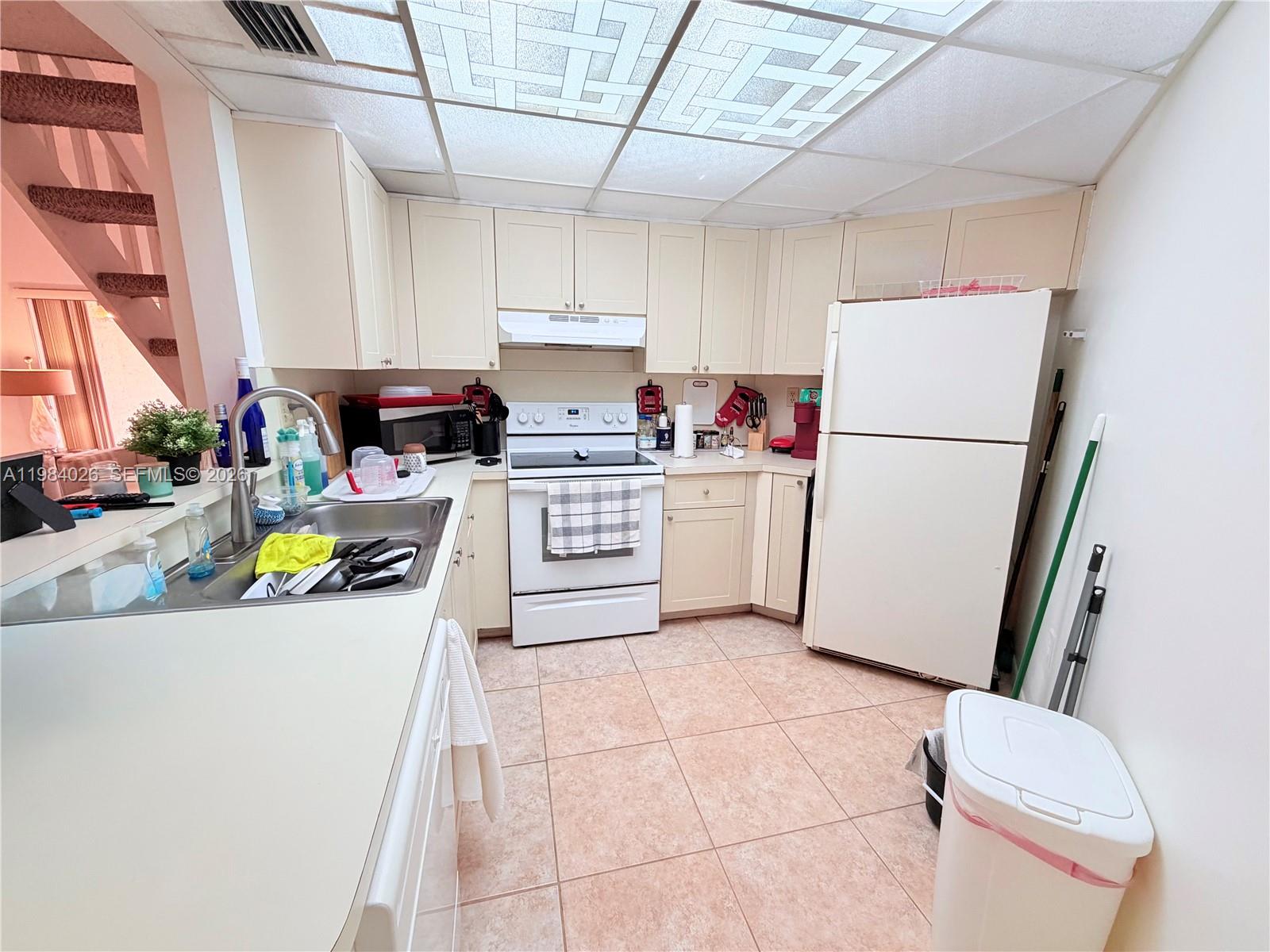 A kitchen features light-colored cabinets, white appliances, a tiled floor, and a drop ceiling — 10233 NW 9 ST # 1, Miami FL 33172, MIAMI, FL