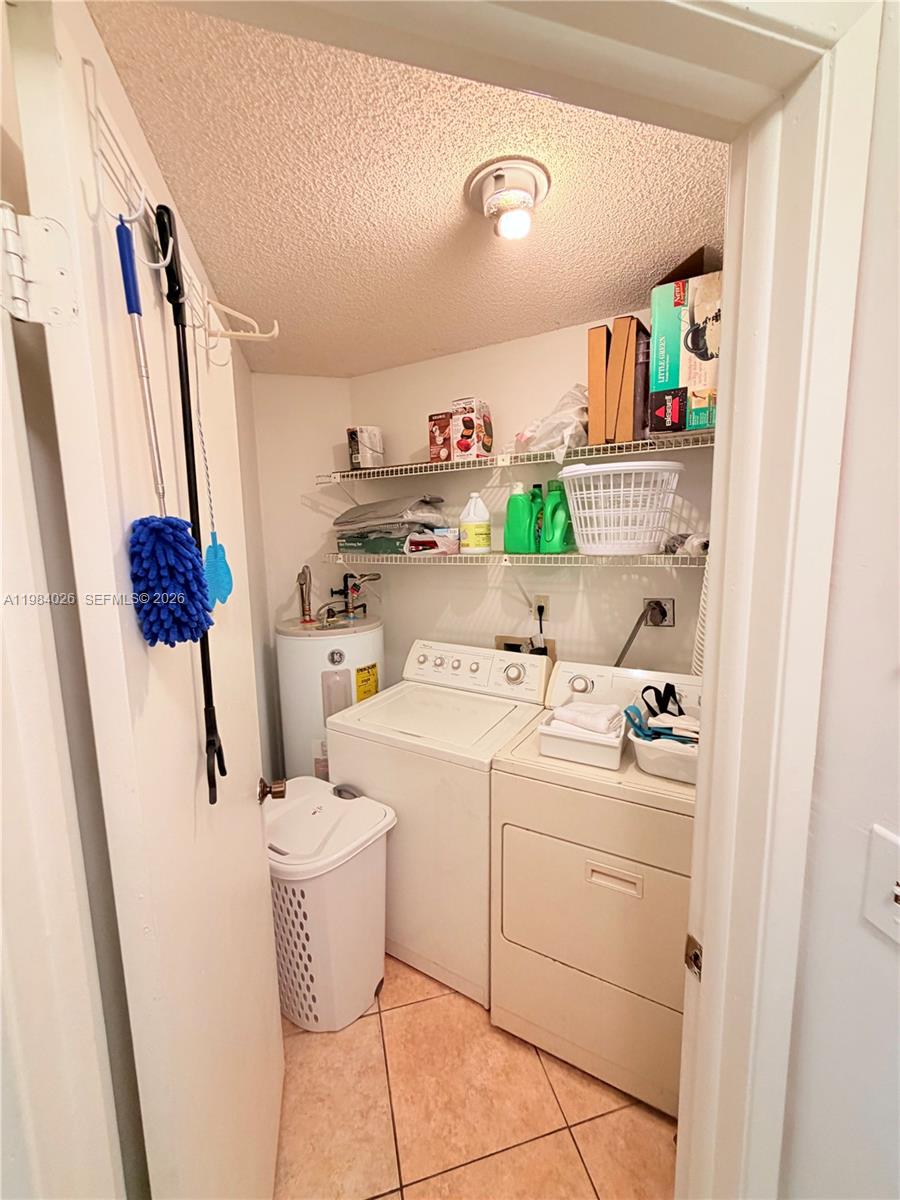 A small laundry closet contains a white washer, dryer, water heater, and wire shelving — 10233 NW 9 ST # 1, Miami FL 33172, MIAMI, FL