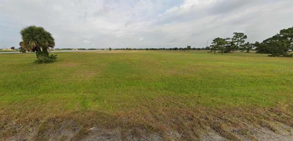 A large, flat, grassy vacant lot features a single palm tree and distant water views — 7 HEMLOCK DRIVE, PLACIDA, FL
