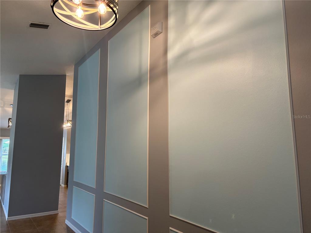 A hallway features light blue wall panels with white trim and a modern light fixture — 908 WOODSTREAM LANE, ORMOND BEACH, FL