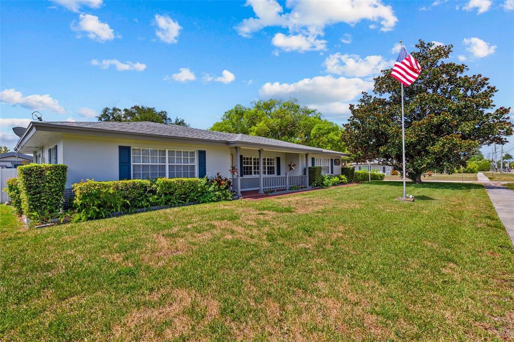 A single-story house with a flag pole and a large tree in the front yard — 2087 DRUID ROAD E, CLEARWATER, FL