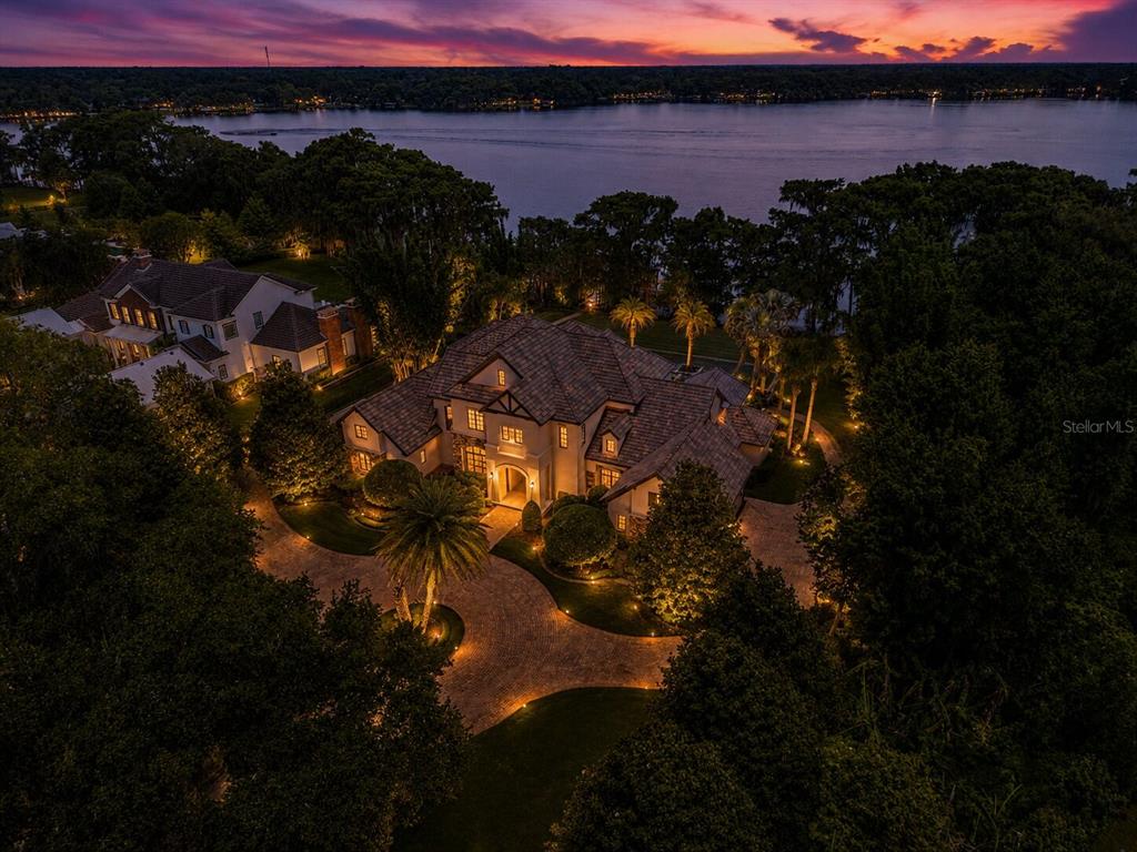 An aerial view of a large house with a paved driveway at sunset by a lake — 680 LAKE MILLS ROAD, OVIEDO, FL