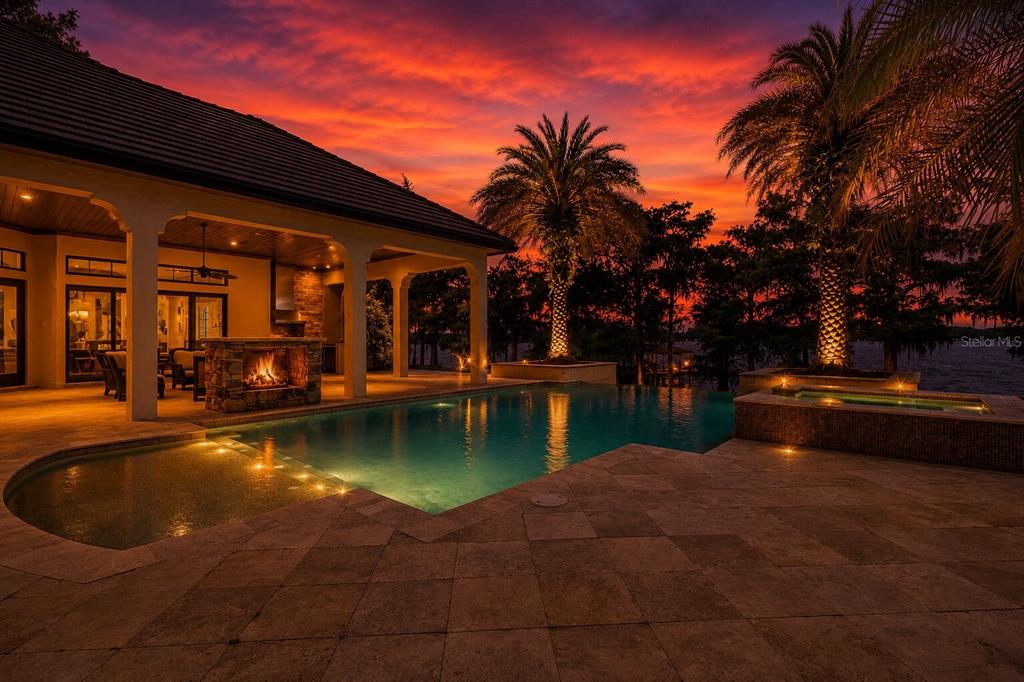 A swimming pool and hot tub sit on a stone patio beside a covered fireplace — 680 LAKE MILLS ROAD, OVIEDO, FL
