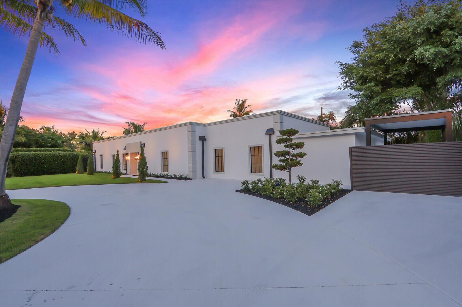 A modern white house with a large concrete driveway and palm trees at sunset — 391 W Riverside Drive, Tequesta FL 33469, TEQUESTA, FL