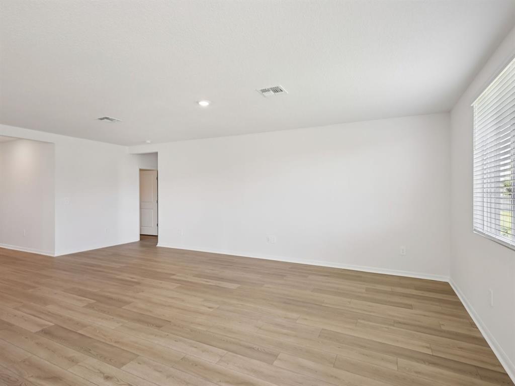 An empty room with white walls, light wood-look flooring, and a window with blinds — 10425 ABUNDANCE GROVE WAY, PARRISH, FL