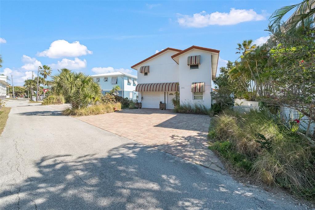 A two-story white house with striped awnings features a paved driveway and palm trees — 8108 PRESIDENTIAL COURT, CAPE CANAVERAL, FL