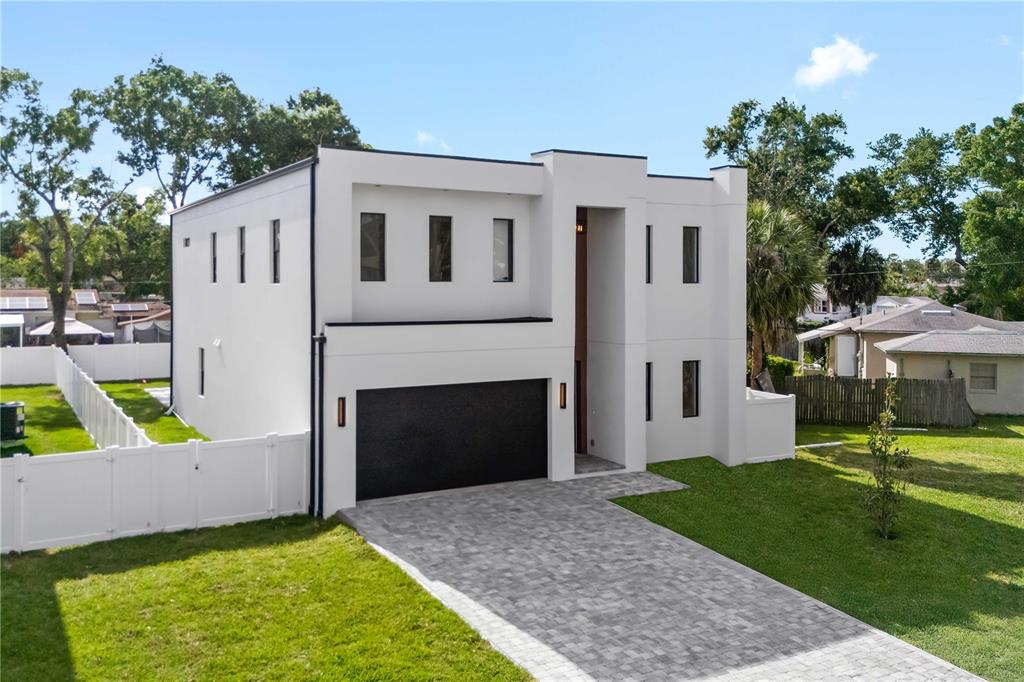 A modern two-story white house features a black garage door and a paved driveway — 2308 1/2 N ELCOE DRIVE, TAMPA, FL